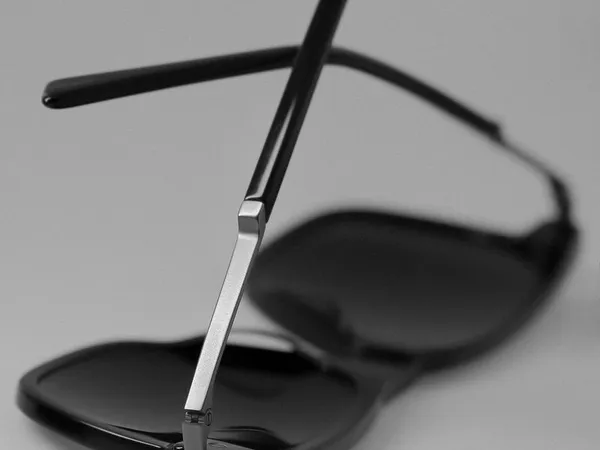 A pair of black sunglasses folded on a grey surface
