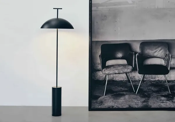 A black dome floor lamp beside a large framed print