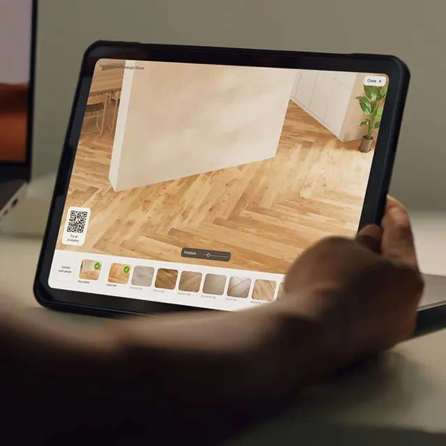 Comparing flooring finishes on a tablet in a real room