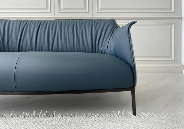 Close-up of a blue leather sofa on a pale wooden floor