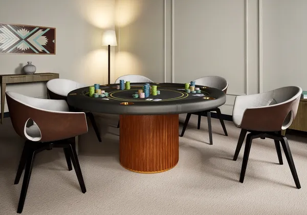 A round poker table laid with chips, surrounded by leather chairs