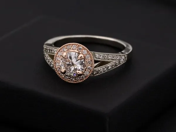 A diamond halo ring resting on a black presentation box