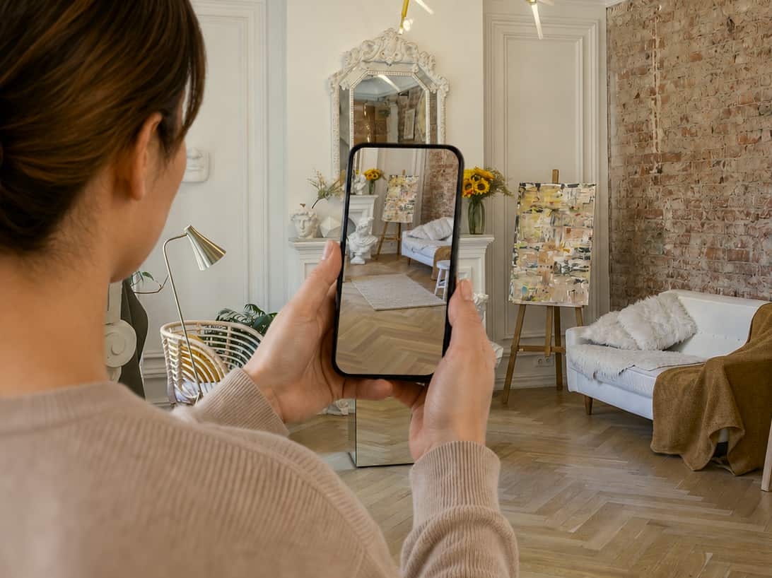 A shopper holds up a phone in a living room; the screen shows the same room with a rug placed on the floor
